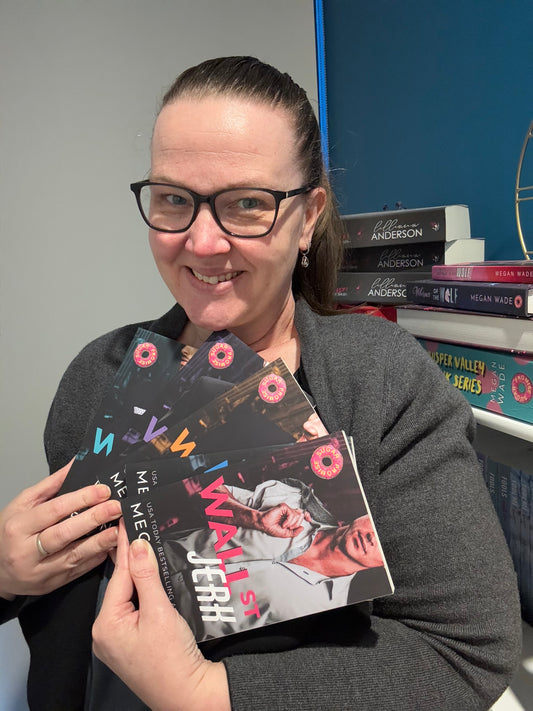 Megan Wade Author holding multiple copies of a book titled 'Wall Street Jerk' .