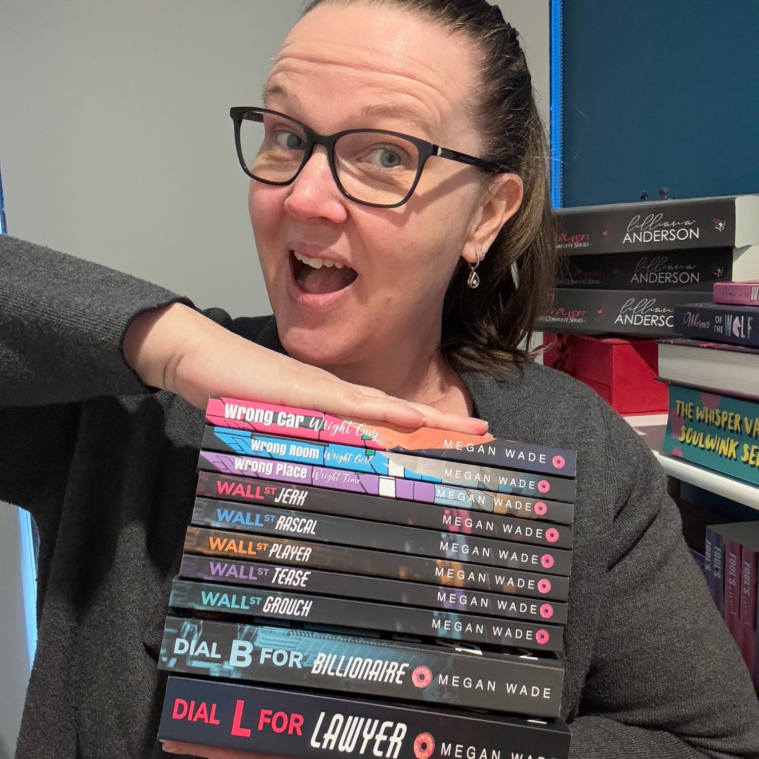 Author holding a collection of books by Megan Wade.